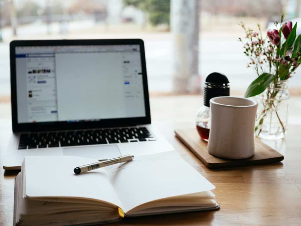 notebook in front of laptop with coffee