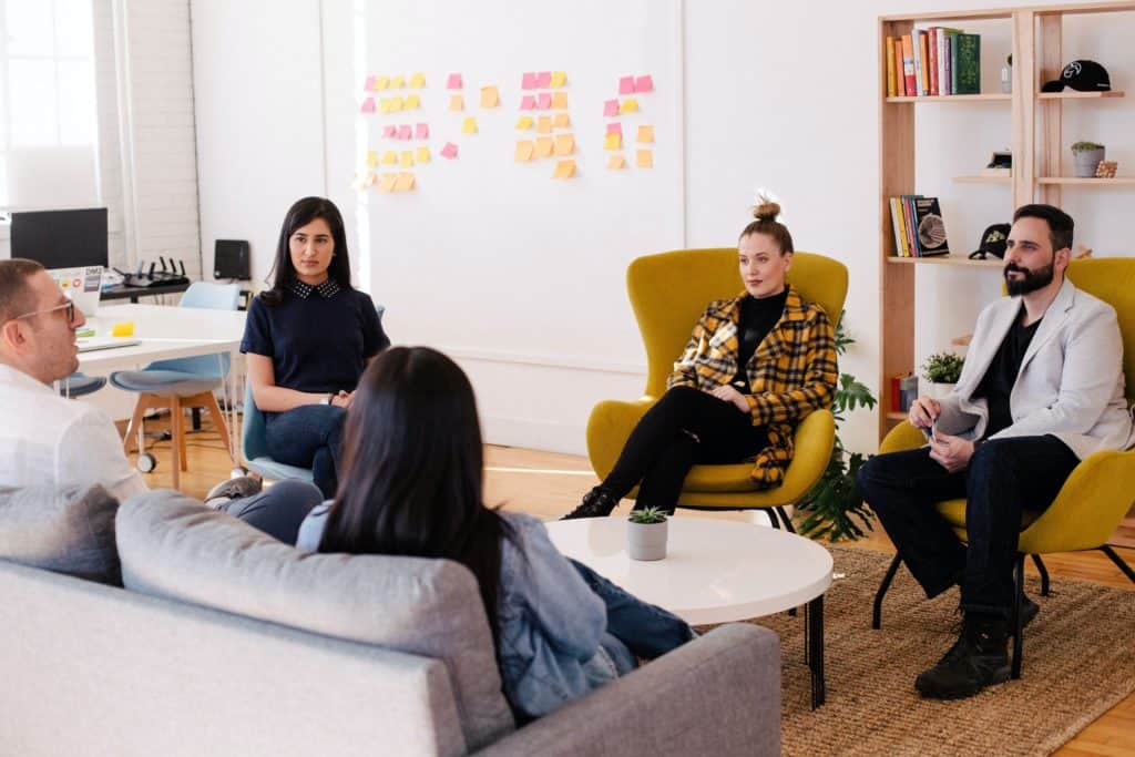 team seated around table with whiteboard